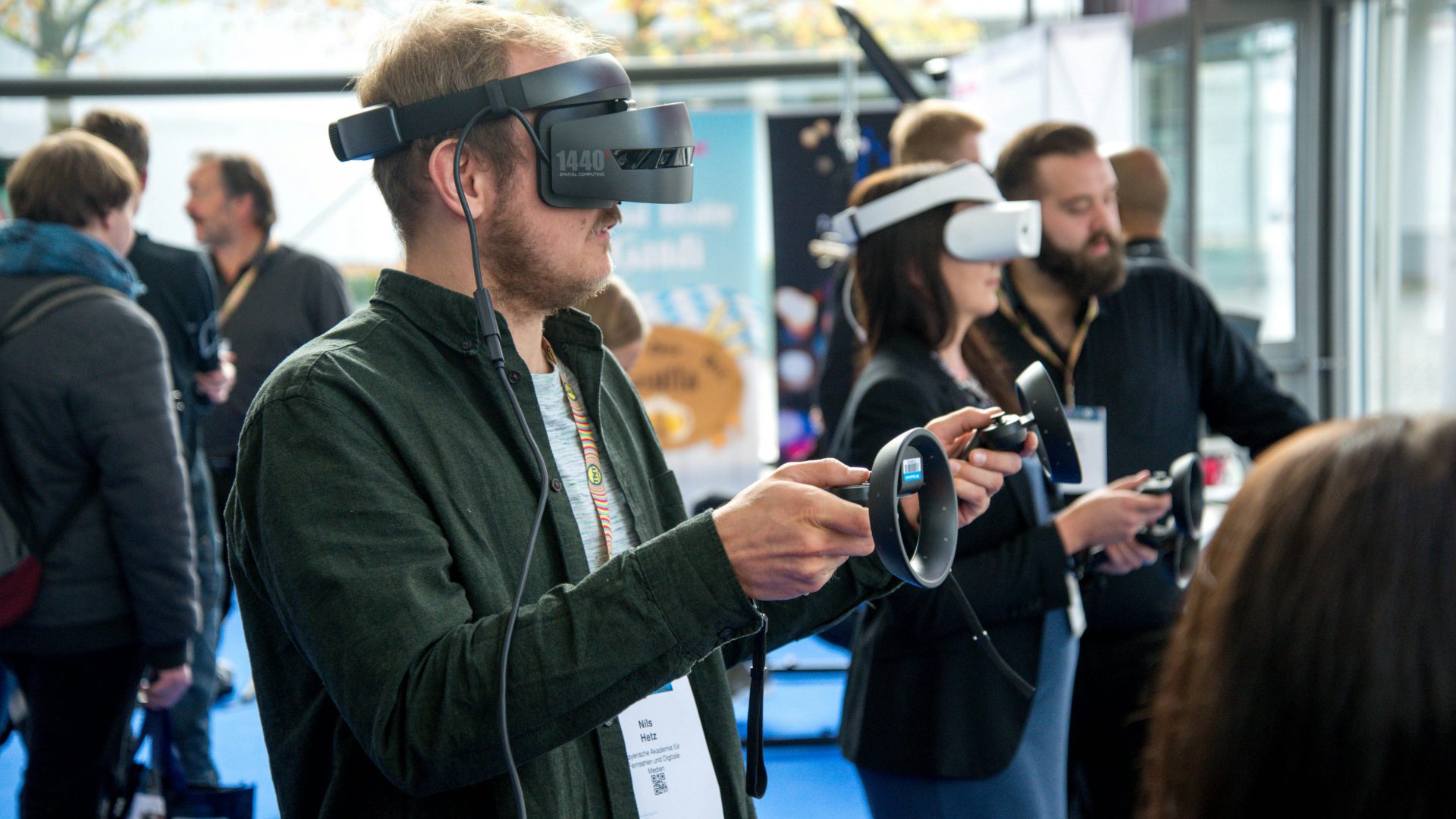 People wearing VR headsets and holding motion controllers, exploring a virtual environment at a demonstration